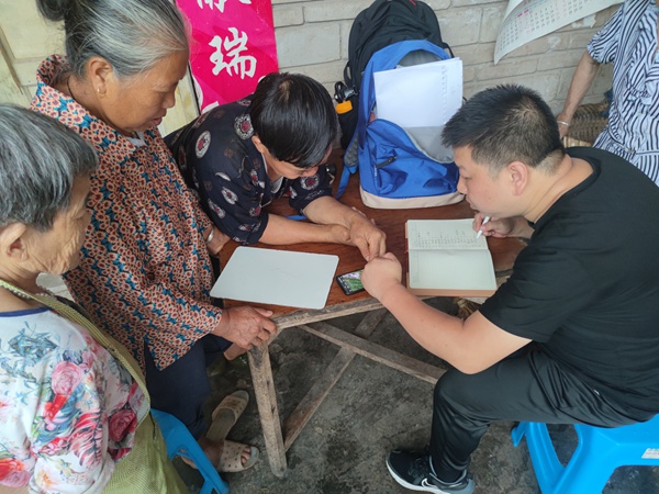 《駐守隊員向老百姓宣傳地災知識》。6月23日，南江地質隊駐守隊員向鋒在雨中巡查時向黃柏鄉三坪村老百姓宣傳地災知識。劉偉攝