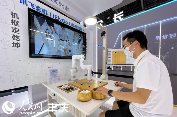 2022智博會科大訊飛展臺的工作人員演示與弈棋機器人對弈。人民網 胡虹攝
