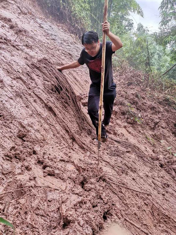 《踏破泥濘》。2020年8月3日，南江地質隊駐守地質隊員戴巖柯前往開州區白鶴街道牛馬騰滑坡為滑坡自動化監測儀器安裝選址。途中遭遇道路塌方前行受阻，戴巖柯一手抓雜草一手撐木杖，踏著泥濘前往目的地。吳叔剛攝