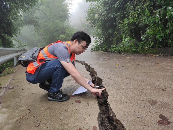 《這個裂縫有點寬》。6月28日，開州區郭家鎮袁家巖滑坡發生險情，南江地質隊地質隊員魏來趕赴現場調查滑坡變形特征。廖學海攝