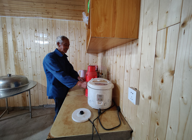 杉板裝飾的屋內，老黨員正熱情地給客人們倒茶。徐俊聰攝