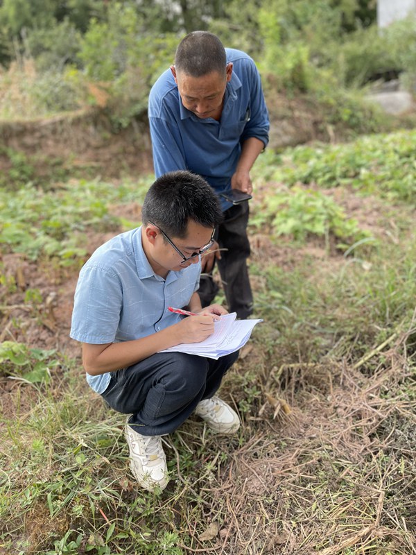 《田間地頭》。9月4日，為摸清武隆中部片區農村房屋周邊地質災害風險，南江地質隊駐守隊員陳旭（前）在武隆區芙蓉鎮堰塘村一處房屋開展邊坡調查，并對房屋信息進行登記。陳剛攝
