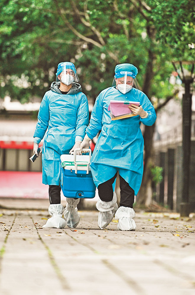 11月17日，北碚區朝陽街道河嘉村社區，“95后”志愿者何鑫(右)與張震在轉運核酸樣本。記者 萬難 攝 視覺重慶