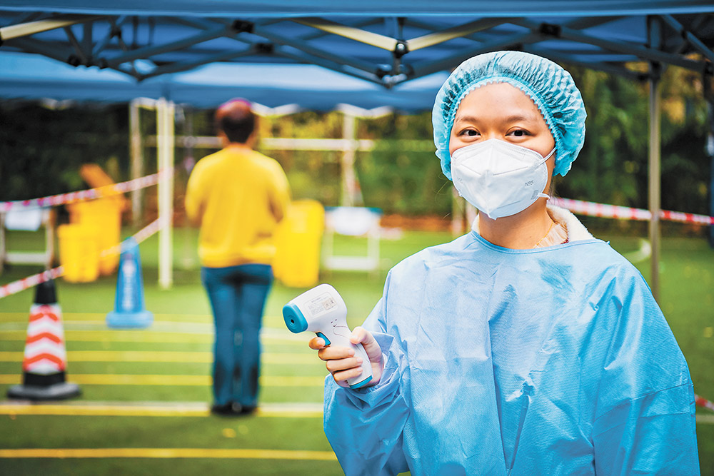 11月17日，綦江區文龍街道半山國際小區檢測點，“95后”志愿者劉柳吟為前來核酸采樣的居民測量體溫。特約攝影 陳星宇 視覺重慶