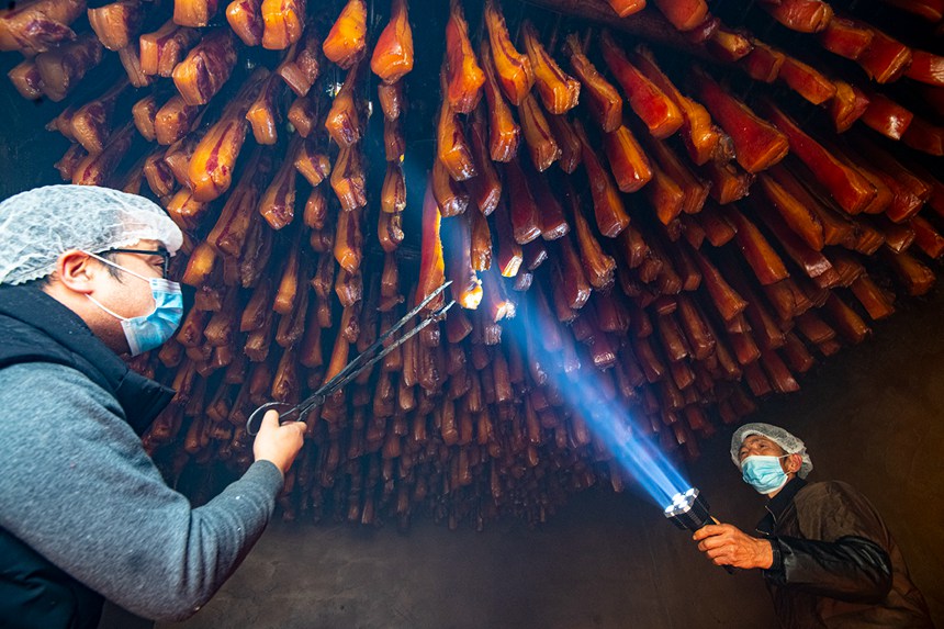 村民在烤臘腸。?冉孟軍攝
