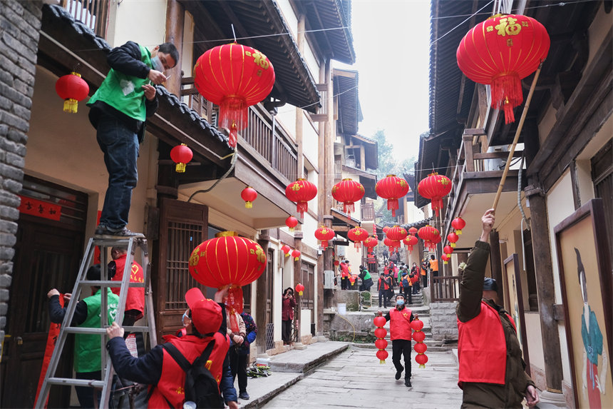 志愿者們正在為黃葛古道敦厚坡段的傳統民居掛燈籠。郭旭攝