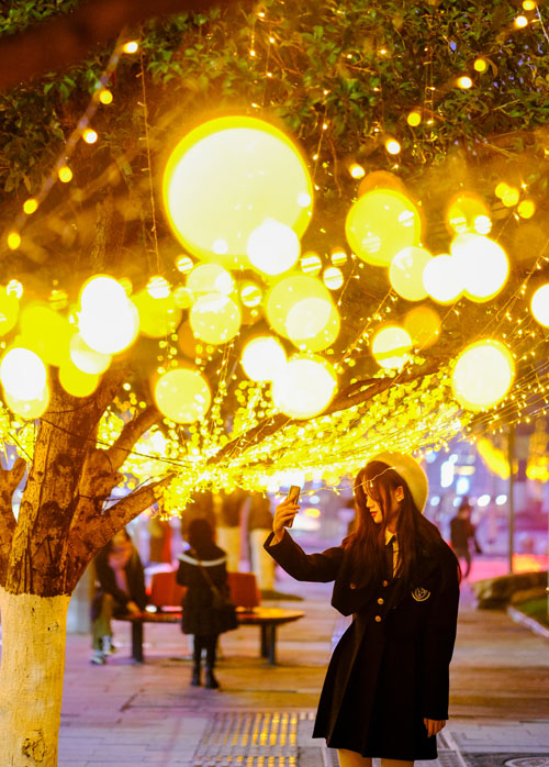 市民在流光溢彩的彩燈前留影。郭旭攝