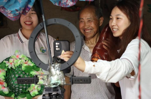 團隊成員幫助村民開通直播賬號并現場試播。重慶商務職業學院供圖