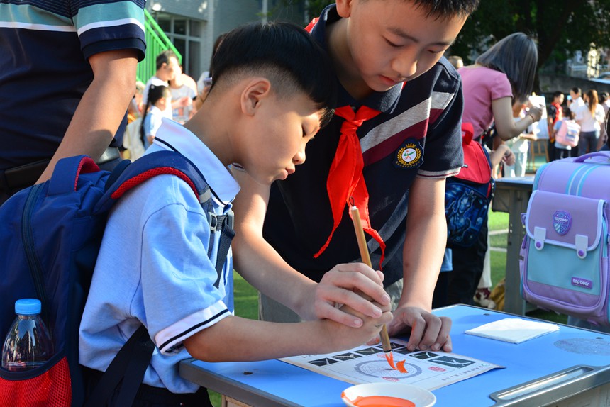 梁山小學高年級孩子帶著新生“開筆習文”，端端正正寫下“人”字。