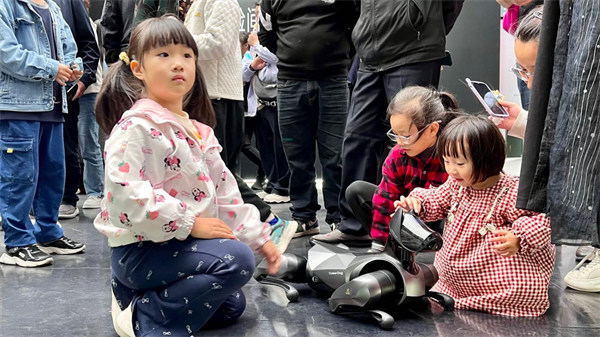 小朋友們與機器狗做游戲。馬春鵬攝