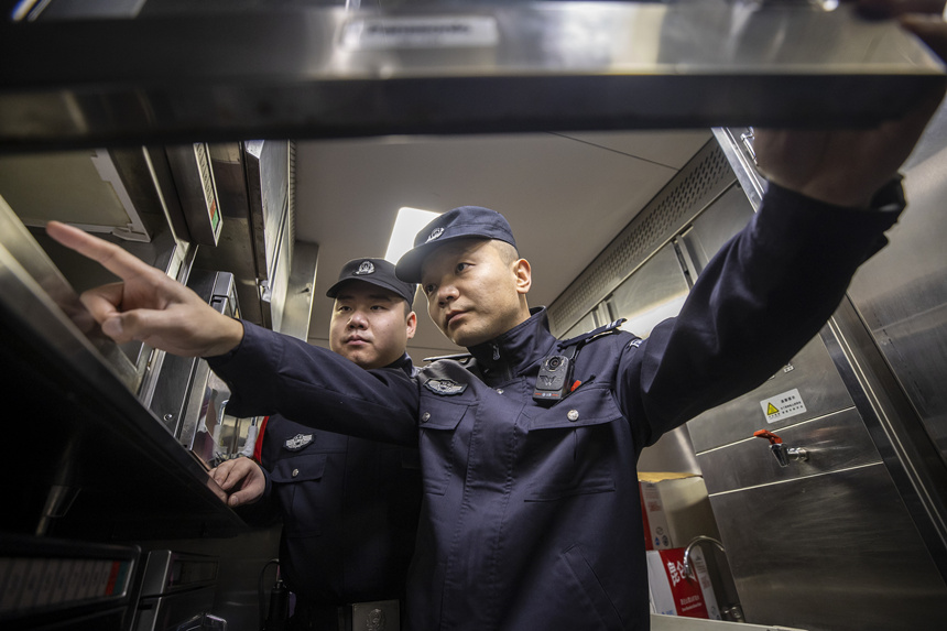 彭聰（右一）在乘警的配合下，對列車電器設備進行檢查。胡勇攝