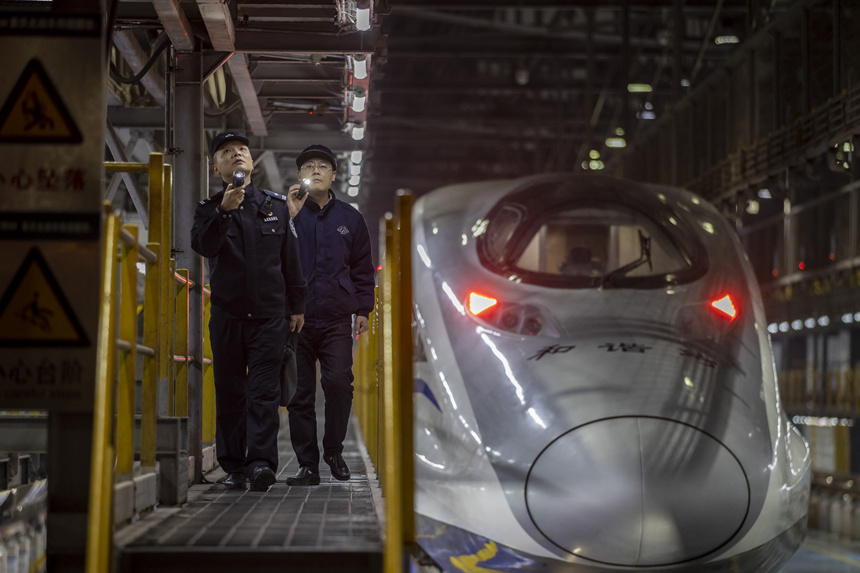 彭聰（左一）在重慶北動車所工作人員的配合下，對檢修庫作業線上的電路阻燃絕緣防護進行檢查。胡勇攝