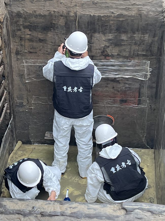 考古人員在墓內清理槨板壁畫。黃偉 攝