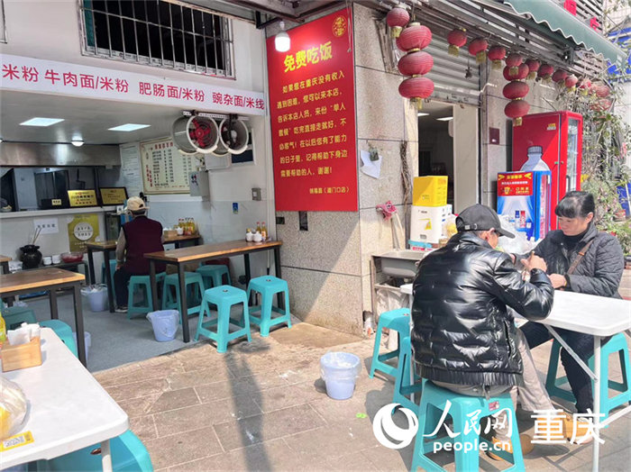 “免費吃飯”的告示就貼在餐館入口右邊的墻上，紅底黃字十分醒目。人民網 馮文彥 攝