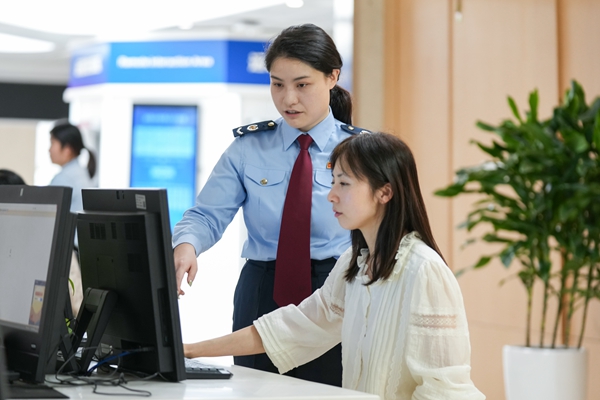 兩江新區辦稅服務廳工作人員輔導納稅人使用電子稅務局進行發票申領的資料圖。郭睿攝