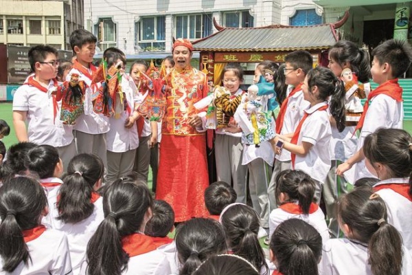 非遺傳承人張賢光給學生講解手掌木偶戲表演技藝。廣安區融媒體中心供圖