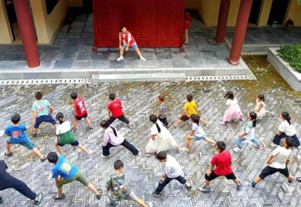 實踐隊隊員帶領留守兒童做熱身運動。重慶旅游職業學院供圖