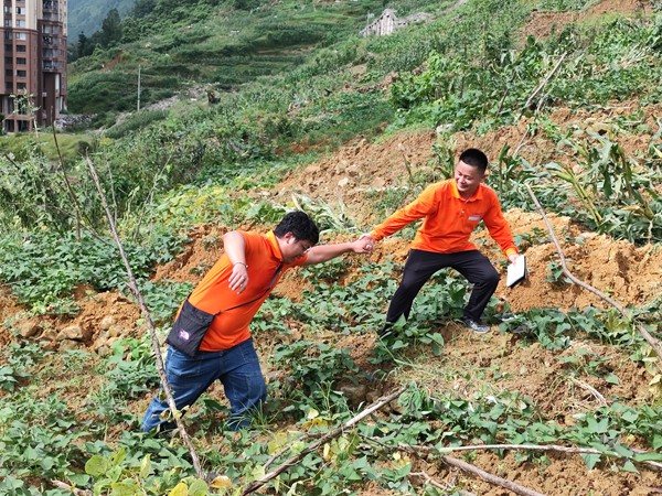 《跋涉》。6月29日，107地質隊的駐守地質工程師陳虹洲在彭水巡查雨后的地災點時深陷泥潭，同事王發英搭手拽他脫離“困境”。李明亮攝