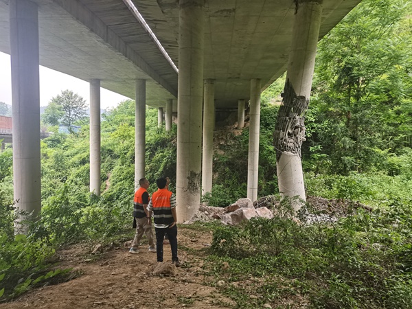 《橋梁受損急人心 搶險應急護安全》。5月21日，川東南勘察公司駐守地質工程師潘笑天（右）、宋宏平會同相關專家，對黔江區阿蓬江鎮犁灣龍洞溝大橋危巖崩塌損毀橋墩處進行應急處置。目前,龍洞溝大橋損毀橋墩已完成更換，橋墩內側已安裝被動防護網。傅柯榮攝