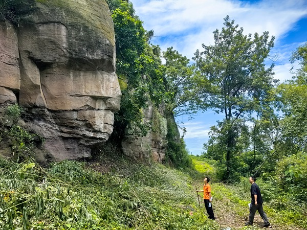 《與巨石對話》。6月21日，川東南勘察公司合川駐守地質工程師袁少游（左）、譚韜對合川區石泉后山危巖進行雨后核查。竹越攝