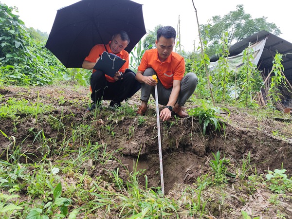 《調查入微》。6月26日，107地質隊駐守豐都地質工程師李?。ㄓ遥?、蔡永俊對雷教滑坡地裂縫下挫深度進行測量。李明亮攝