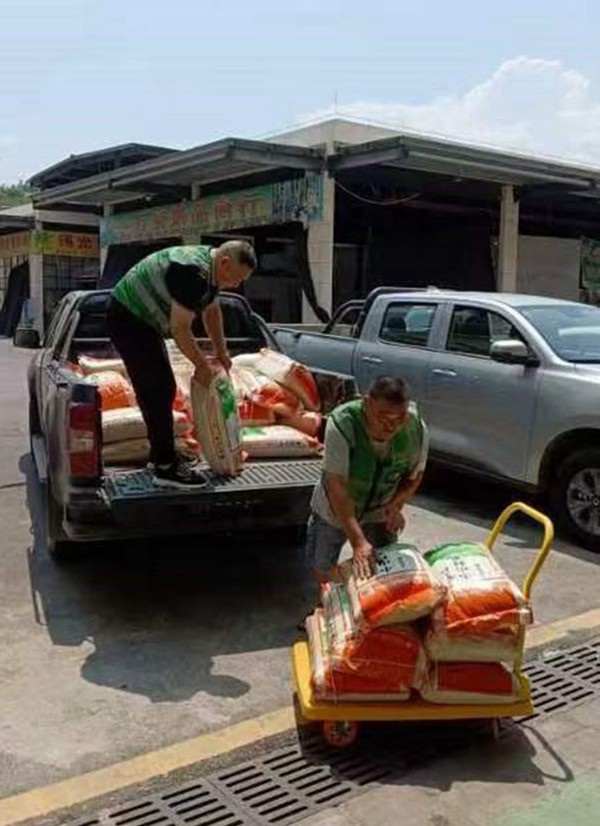 高溫天氣下，配送人員將一箱箱、一袋袋的食材裝車、卸車。車輛啟動，配送之旅正式開始。豐都實業供圖。