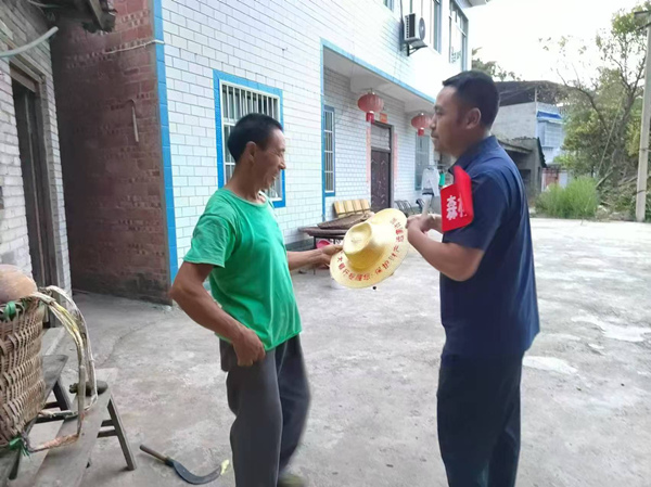 光大銀行重慶分行駐奉節縣長凼村駐村書記向村民贈送印有防詐宣傳語的農用草帽。光大銀行重慶分行供圖