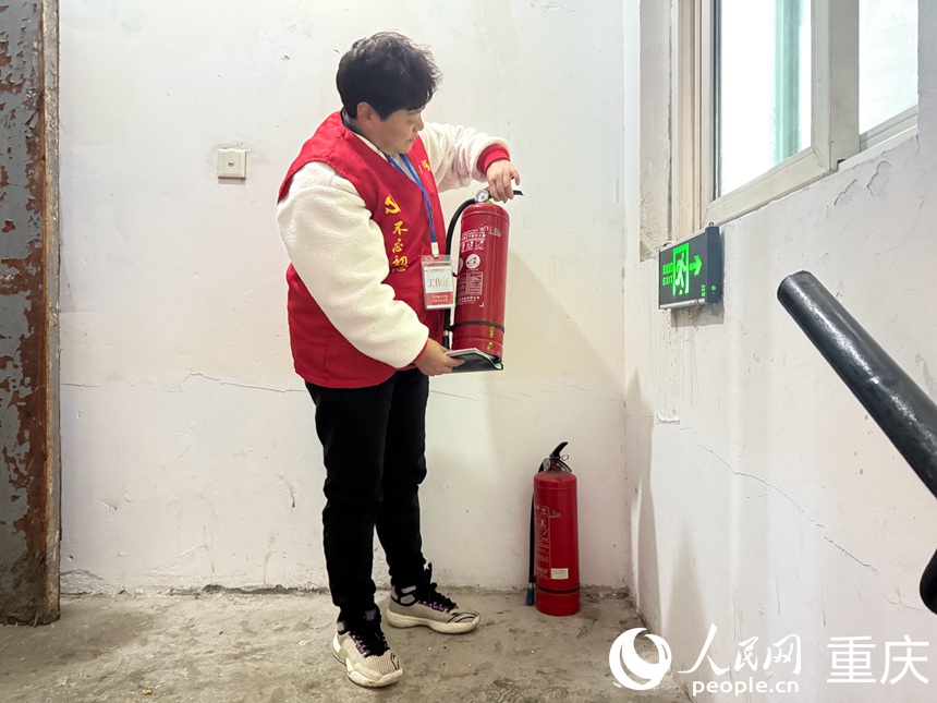 文登群認真檢查樓梯間擺放的滅火器是否能正常使用。人民網記者 胡虹攝