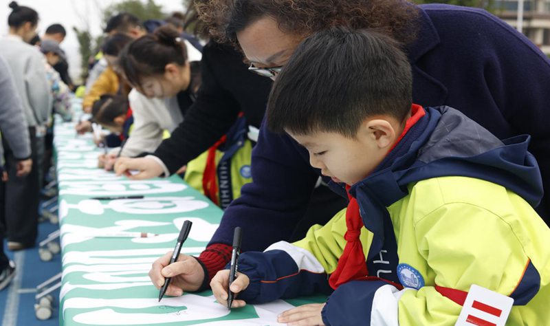 學生和家長在綠色橫幅上寫下祝福語。北碚區兩江春暉小學供圖