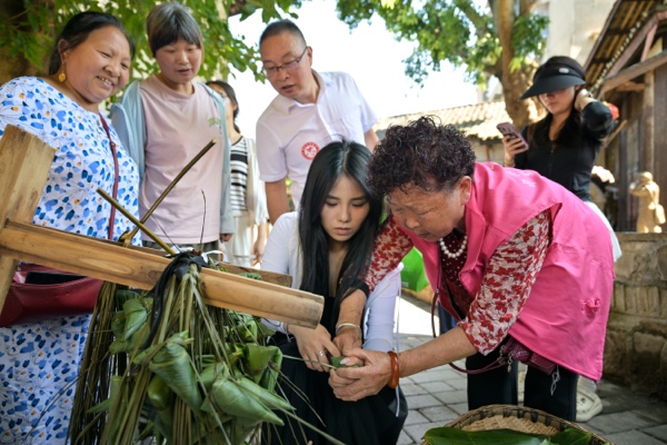 游客在當地居民的指導下包粽子。綦江區委宣傳部供圖