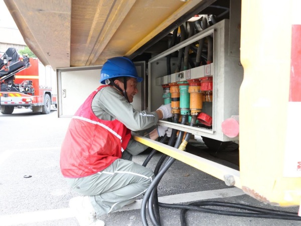 國家電網重慶電力（城口綜合）紅巖共產黨員服務隊隊員陳煉將連接有考點線路的電纜接入中壓電源車。國網城口供電公司供圖