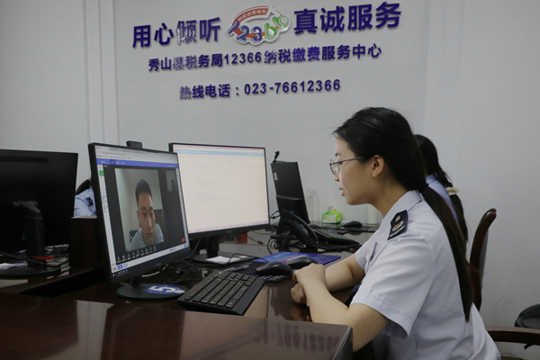 在秀山縣稅務局12366納稅繳費服務中心，稅務人員正通過虛擬窗口與企業辦稅人員視頻連線，辦理跨區域涉稅業務。張雯惠攝