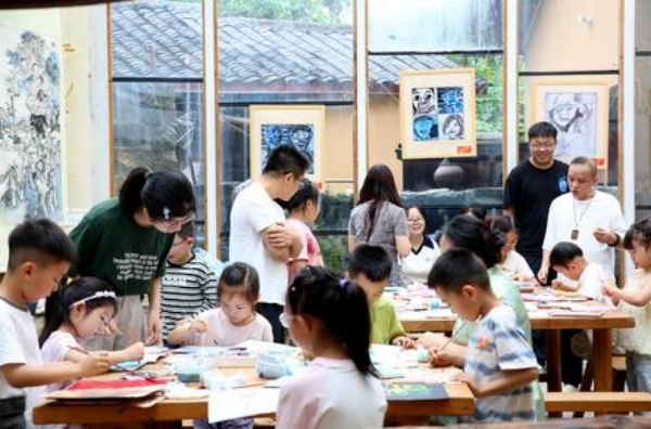 孩子們在大學生志愿者的指導下制作版畫。張夢寒攝