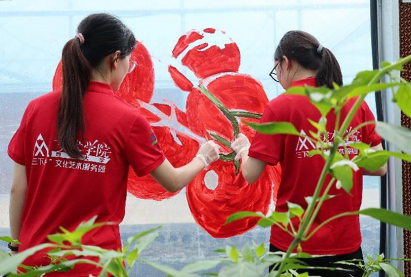 志愿者在大棚外立面進行主題繪畫創作。西南大學供圖