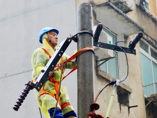 國網重慶市區供電公司搶修人員冒雨對10千伏沙北街柱上變壓器進行搶修。韓薇攝