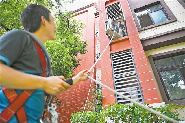 8月5日，南坪實驗金科小學，工人正在吊裝空調外機。近日，南岸區啟動“清涼工程”，將為58所中小學校統一安裝空調共3650臺。記者 謝智強 攝/視覺重慶