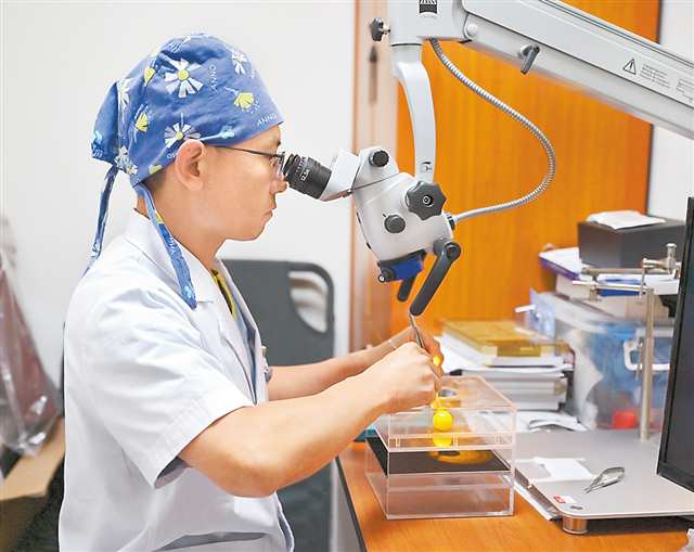 周建軍在顯微鏡前利用葡萄練習傷口縫合。