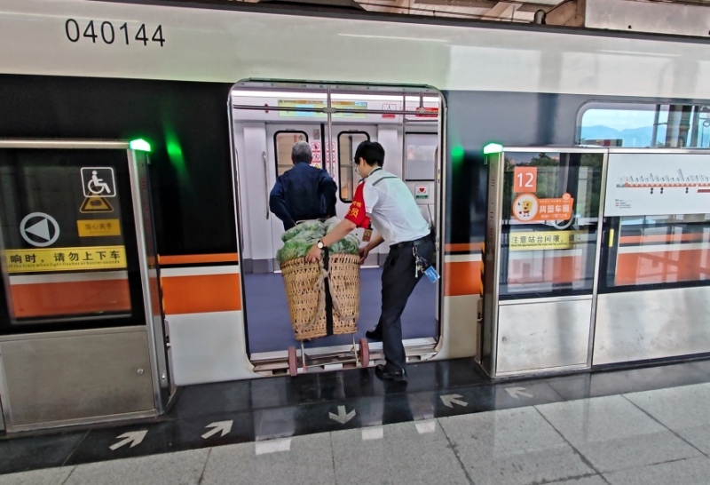 工作人員幫菜農將背簍運進地鐵車廂。重慶軌道四號線建設運營有限公司供圖