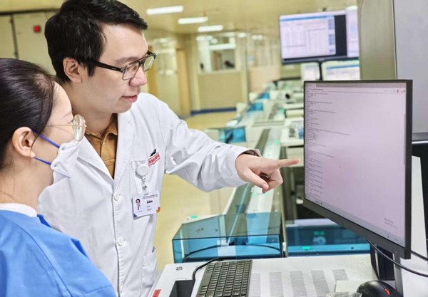 實驗室工作人員與工程師討論系統內容調整。重慶醫科大學附屬第三醫院（方大醫院）供圖