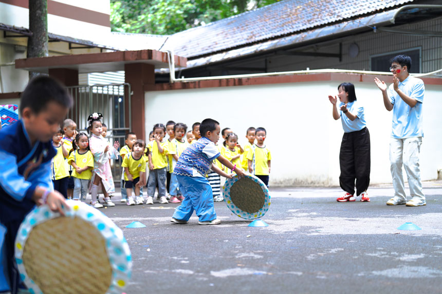 兒童們體驗壯族滾簸箕。劉宇飛攝