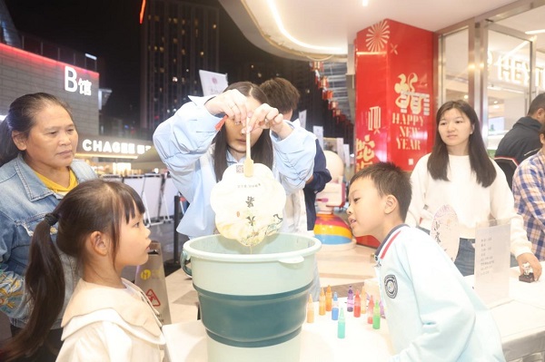 年輕市民用印有中醫藥文化知識的紙扇體驗漆扇制作。曾英豪攝